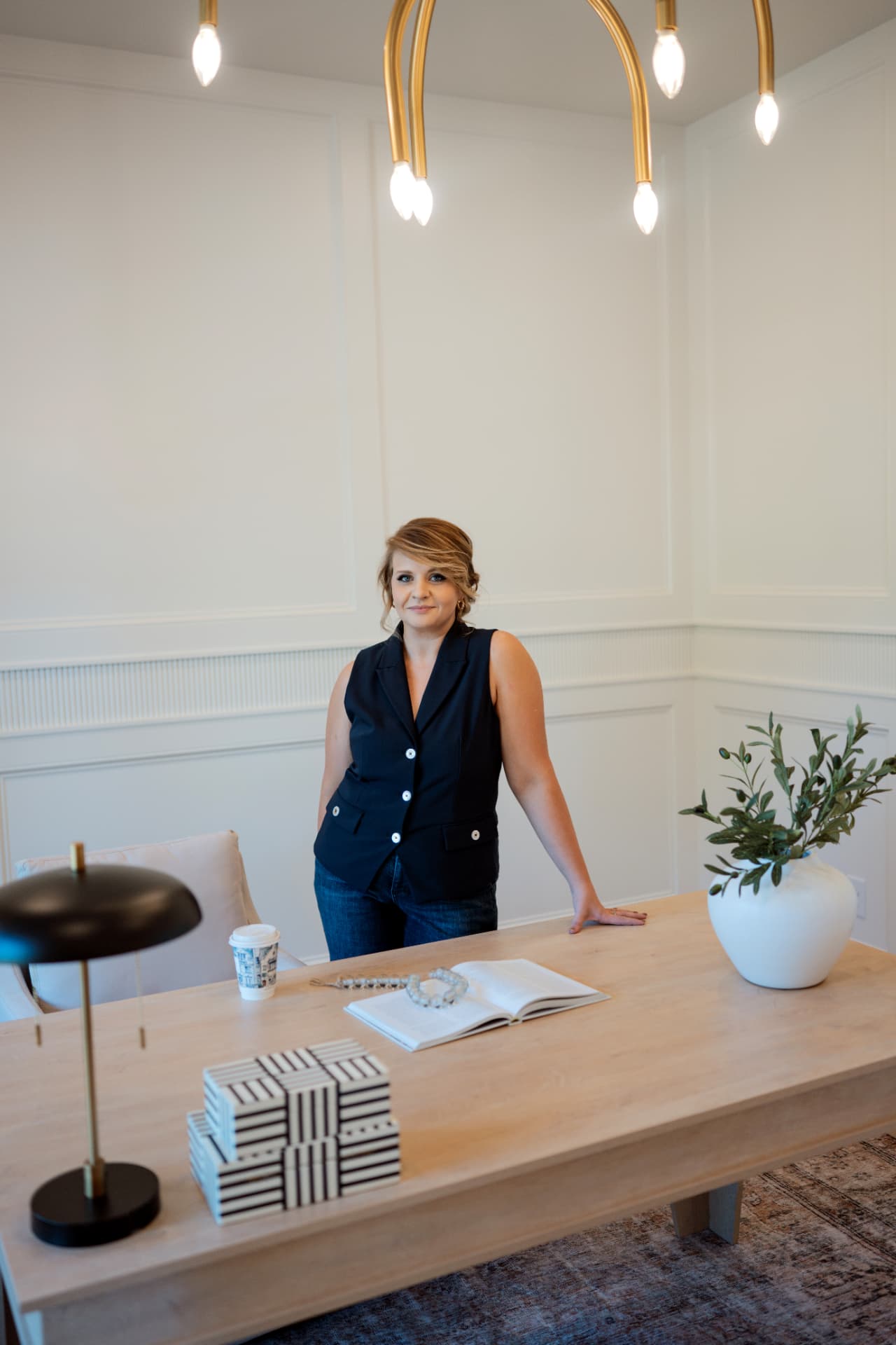 Gabby Brayton standing at her desk beneath a gold office light